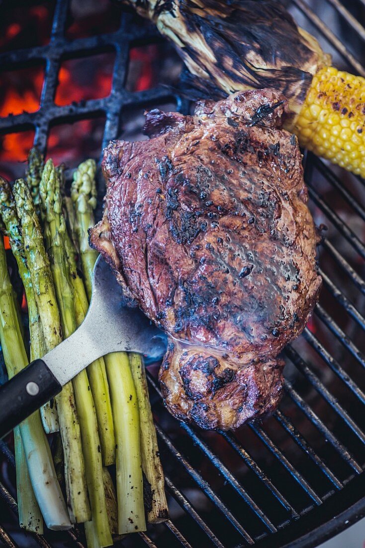 Rib-Eye-Steak, grüner Spargel und Maiskolben auf dem Grill