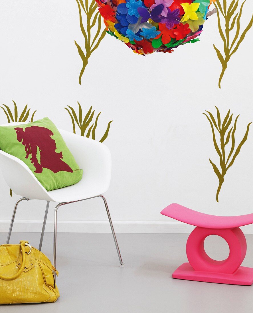 DIY wall design with green stencilled pattern, white armchair with cushion, yellow leather bag and pink stool