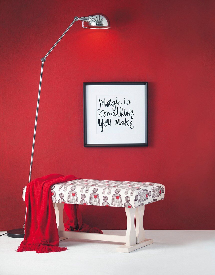 DIY bench made from former wooden coffee table arranged with framed motto on red wall and standard lamp