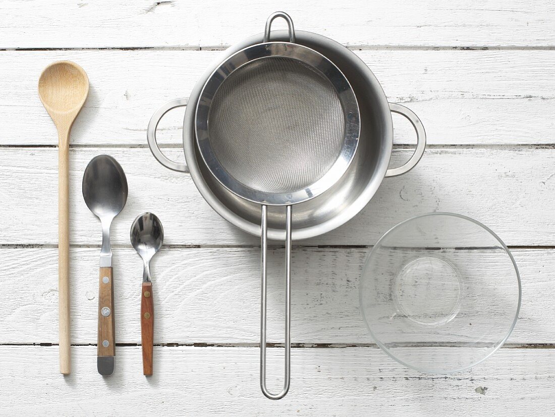 Assorted kitchen utensils: spoons, a saucepan, a sieve and a glass bowl