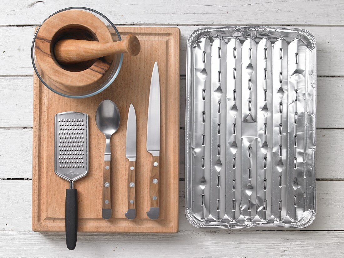 Assorted kitchen utensils for barbecuing: a pestle and mortar, a grater, cutlery and a grill tray