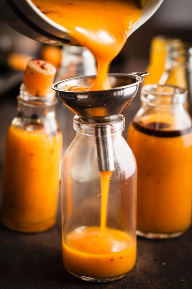Veganen Kürbisshot mit Chiliflocken in Flasche einfüllen