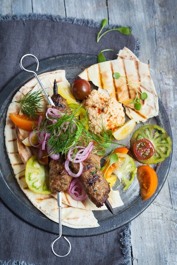 Kofte kebabs with houmous and tomato salad on pitta breads