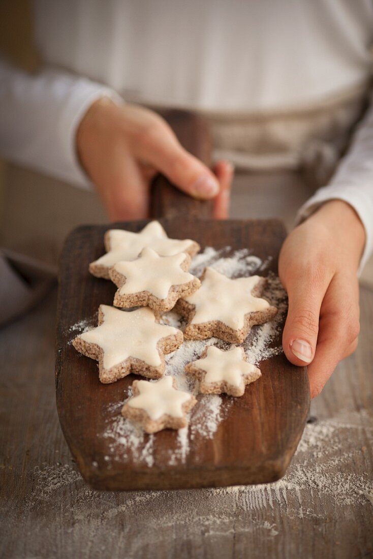A woman holding cinnamon stars on a wooden board