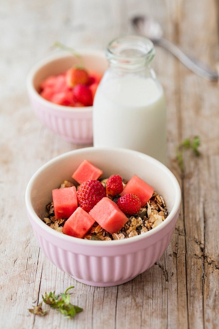 Granola with strawberries and watermelon and a bottle of oat milk