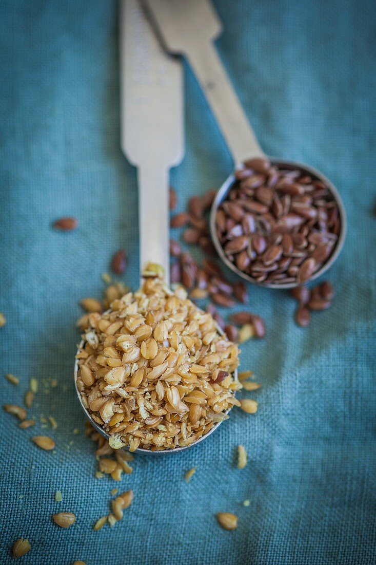 Flaxseed, whole and peeled, on two spoons
