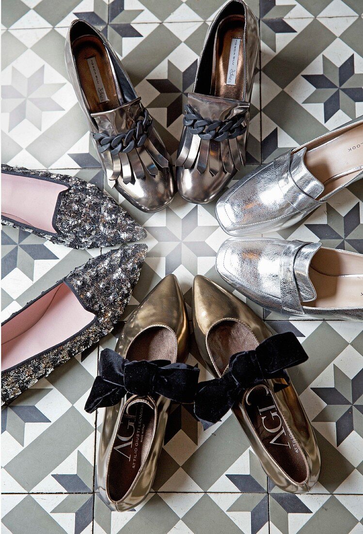 Verschiedene Loafers im Metallic-Look auf gemustertem Boden