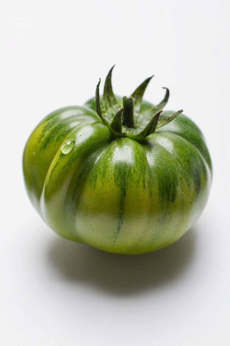 Eine grüne Tomate vor weißem Hintergrund