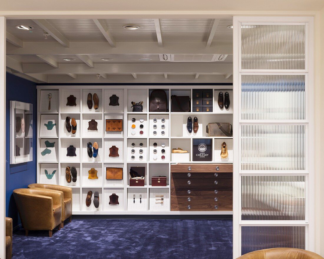 Shoes and accessories on white, custom shelving in masculine sales room