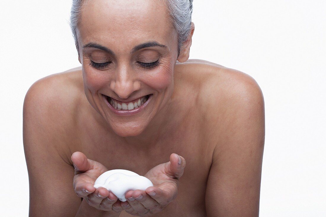 An older woman using facial cleanser