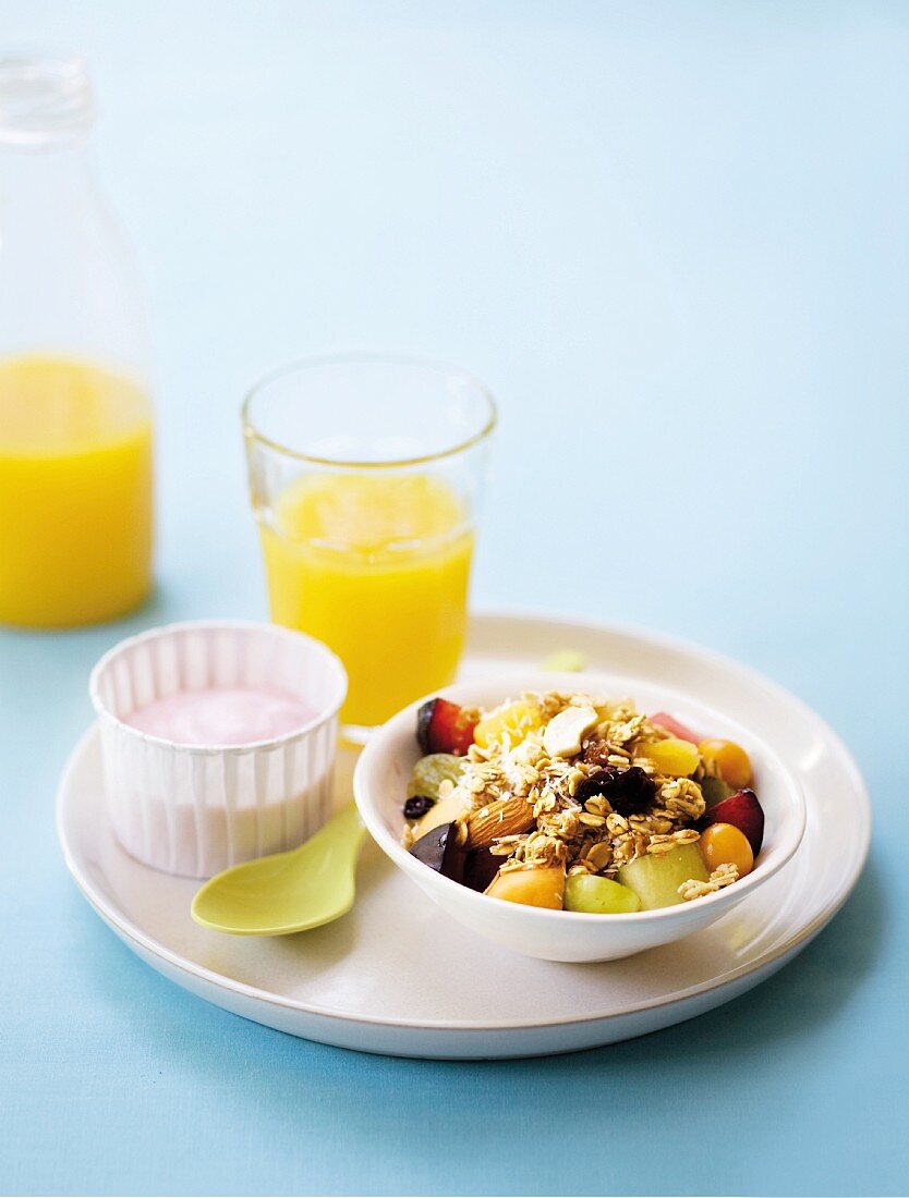 Frühstücksmüsli mit Obst, Joghurt und Orangensaft