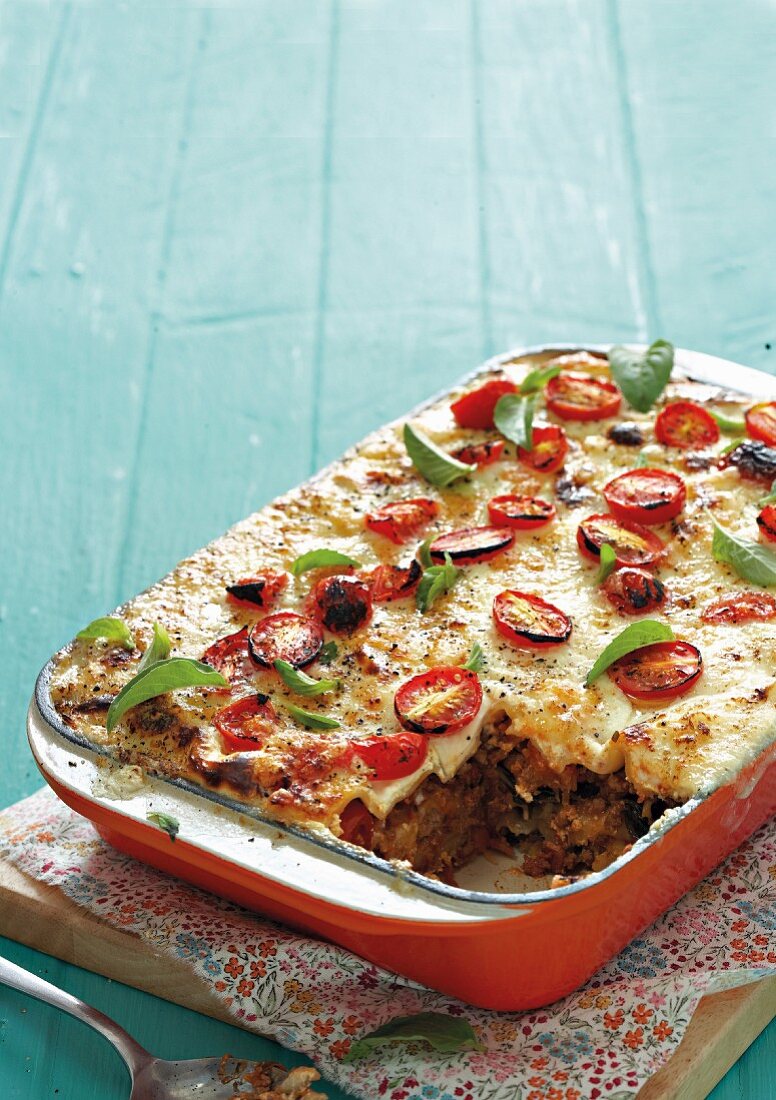 Classic lasagne in a casserole dish with one slice removed