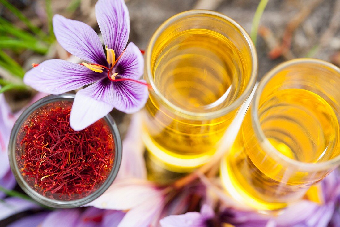 An arrangement of saffron threads, saffron flowers and dissolved saffron in glasses