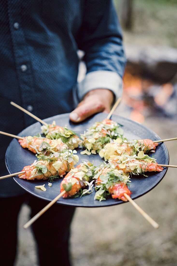 Grilled marron on a stick with citrus butter, flowers and herbs