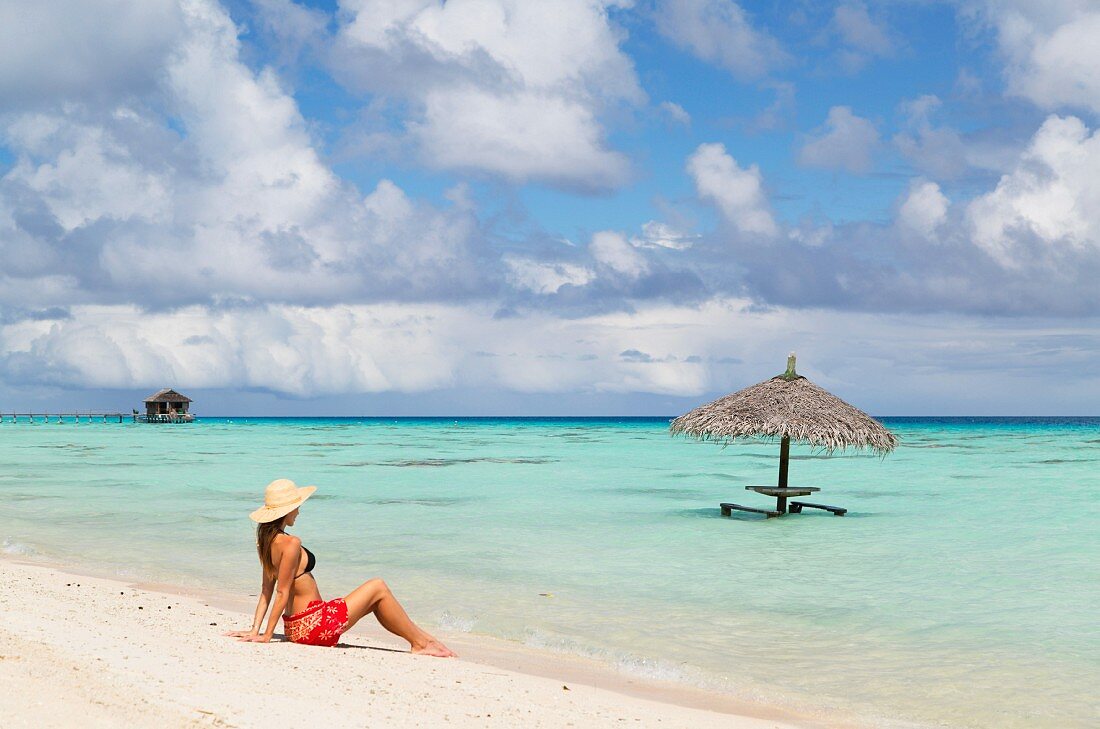 Frau sitzt am Strand, Fakarava, Tuamotu-Inseln, Südpazifik