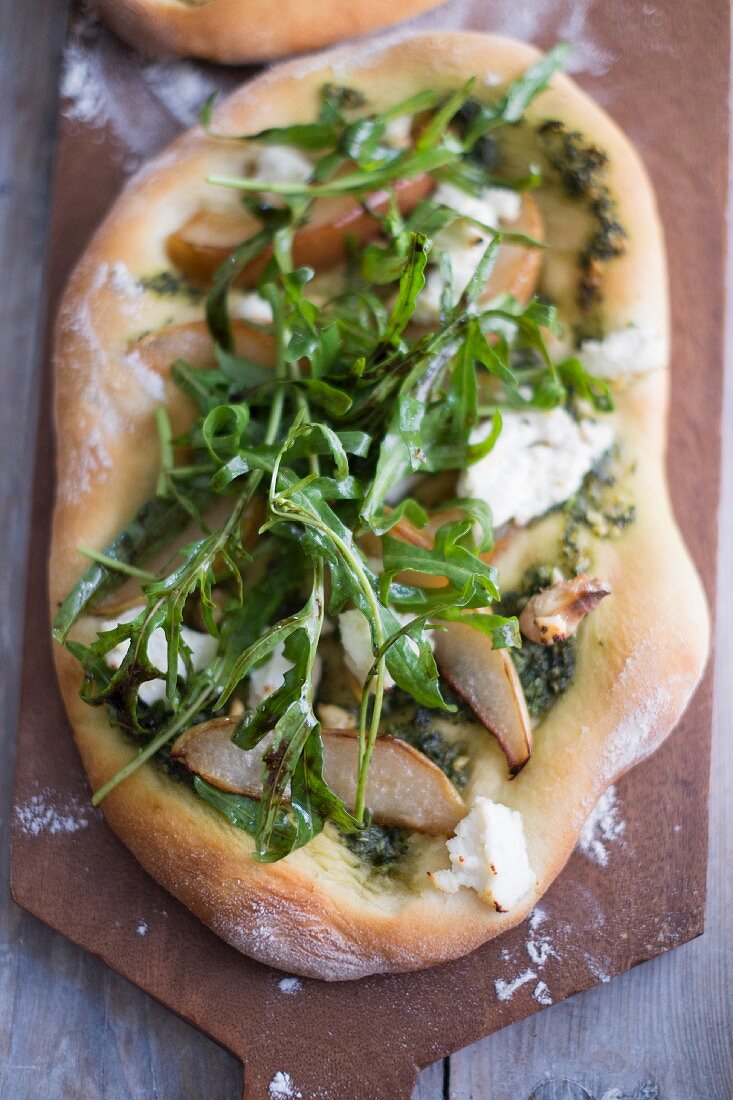 Vegan pizza with pear, rocket, pesto and walnut