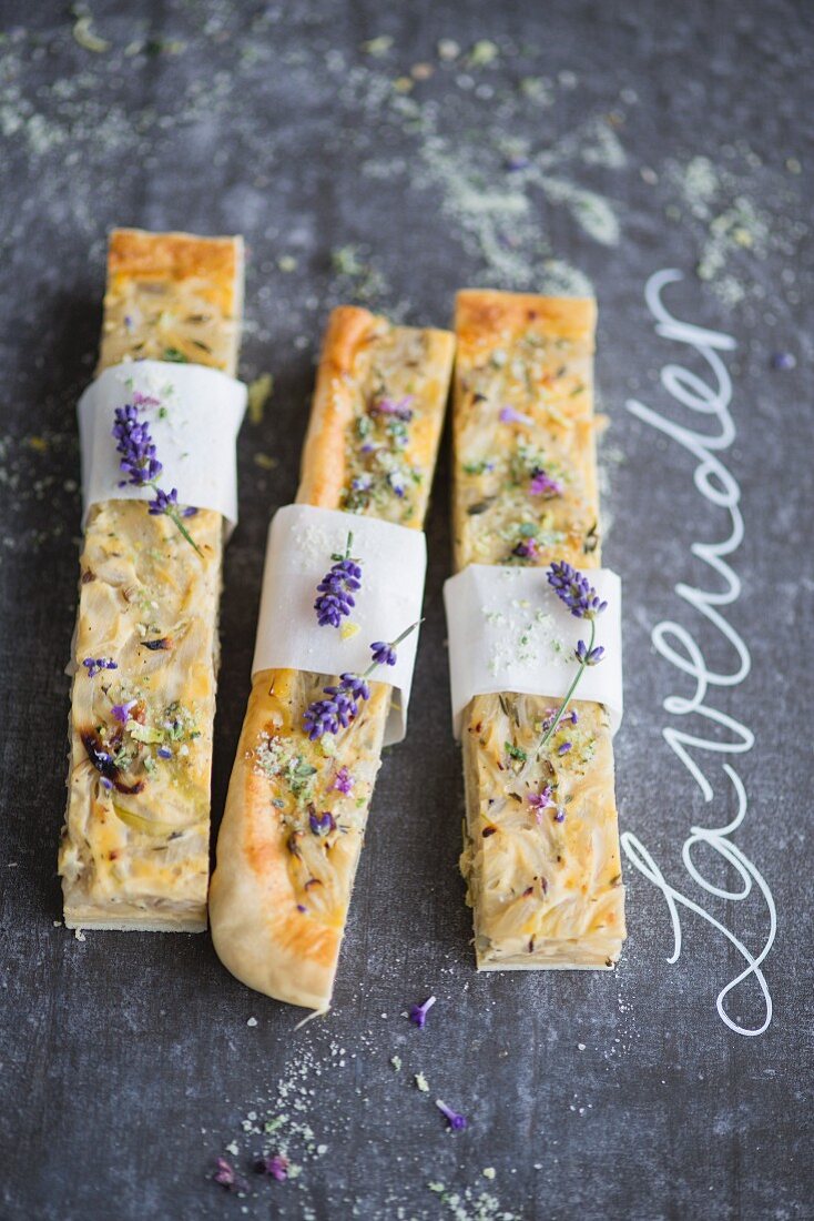 Zwiebelkuchenstücke mit Lavendelblüten und Basilikumsalz