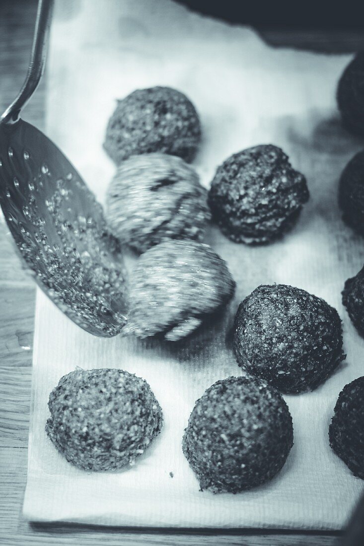 Fried falafel being drained on kitchen roll (black and white image)