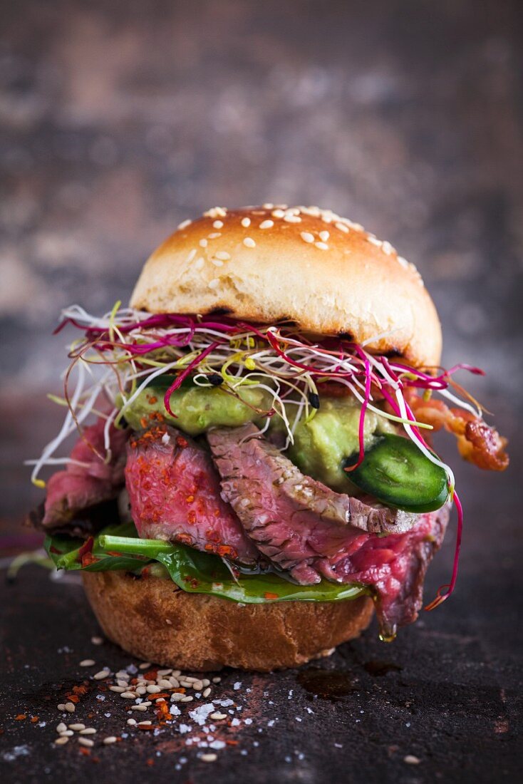A mini burger with roast beef, jalapenos, spinach and bean sprouts