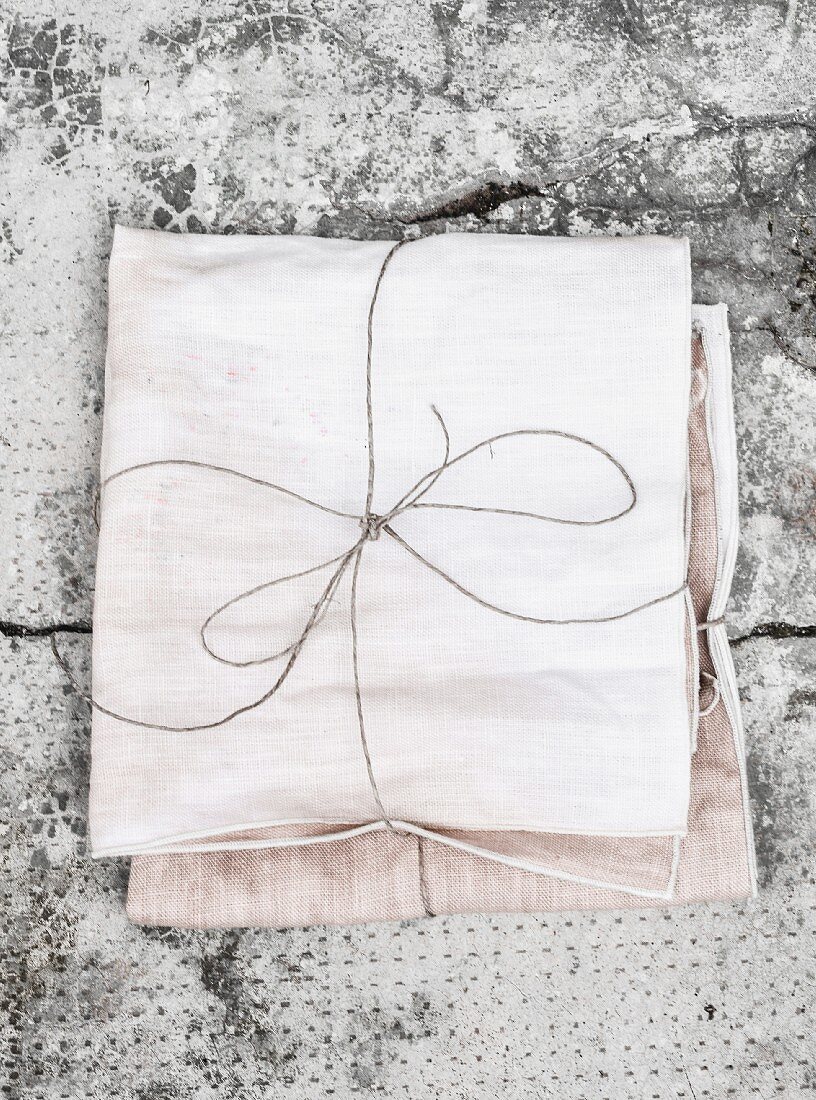 Bundles of hand-dyed fabric tied with cords on grey surface