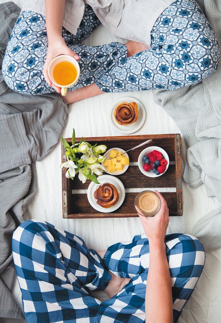Frühstück im Bett mit Obst, Zimtschnecken, Kaffee und Tee