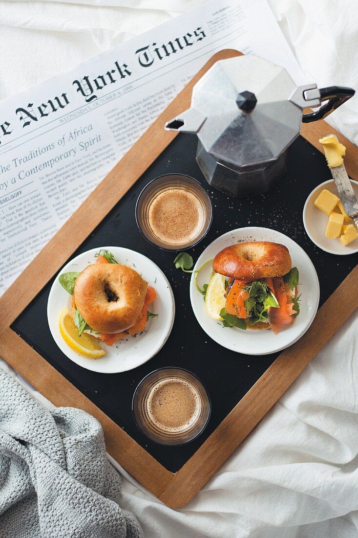 Breakfast in bed with bagels, coffee and newspaper