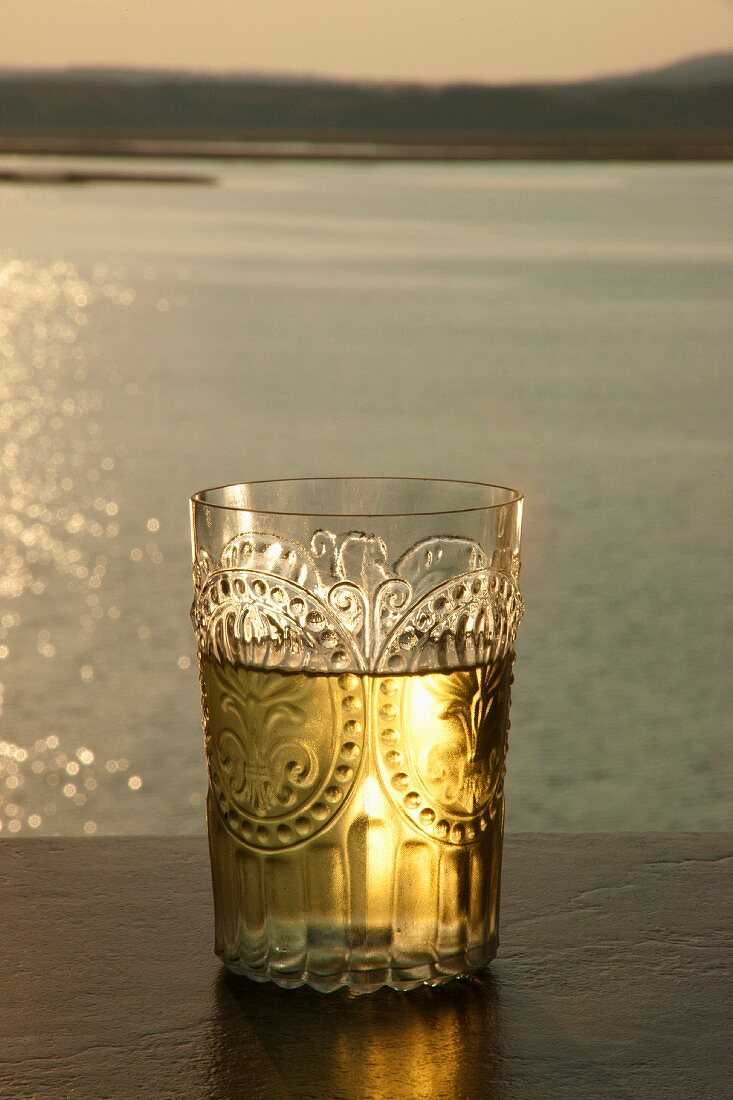 Elegantes Weissweinglas bei Sonnenuntergang am Fluss