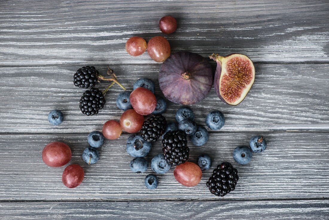 Brombeeren, Blaubeeren, Heidelbeeren, Trauben und Feigen auf Holzuntergrund