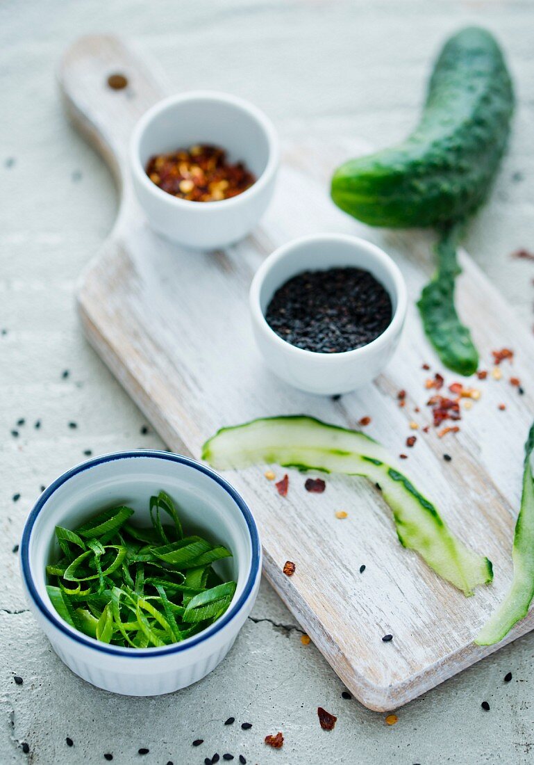 Ingredients for cucumber salad with chilli flakes, spring onions and sesame seeds