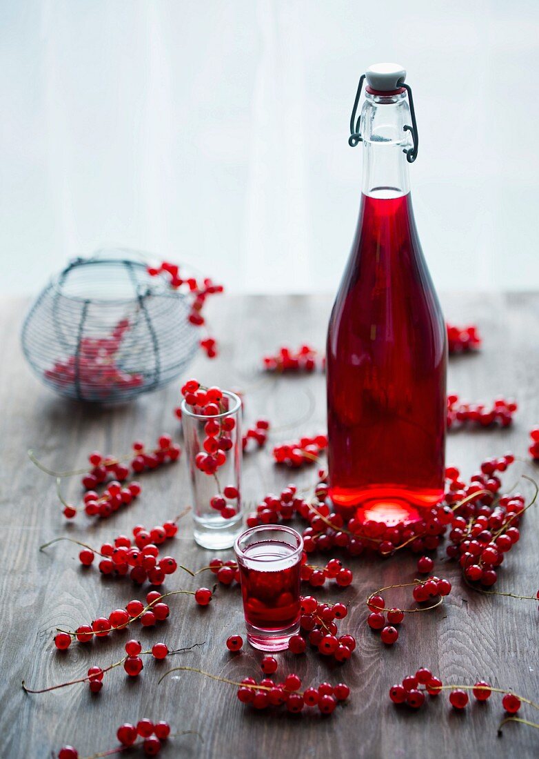 Roter Johannisbeerlikör in Flasche und Glas