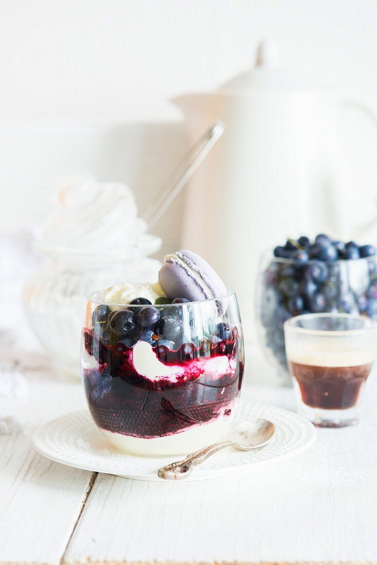 A layered desert with blueberry purée and mascarpone & vanilla cream, decorated with a macaron