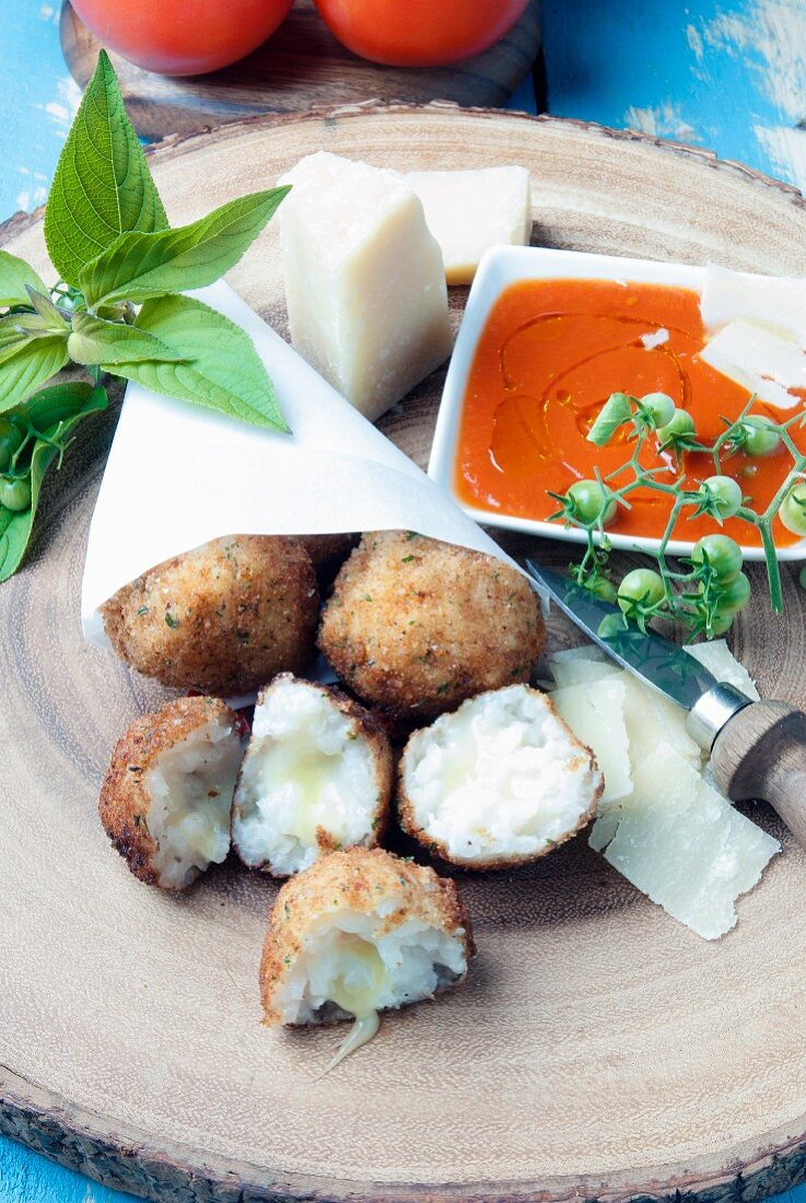 Arancini with cheese in a paper bag, served with tomato sauce and Parmesan