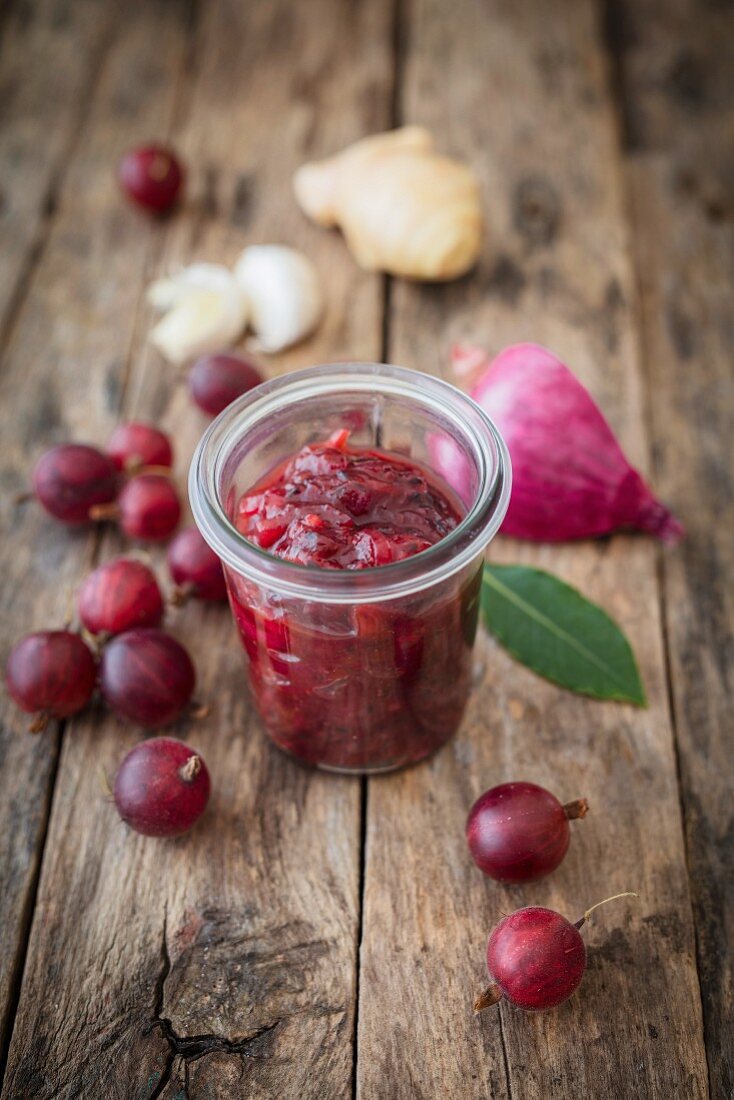 Gooseberry chutney in a glass surrounded by ingredients