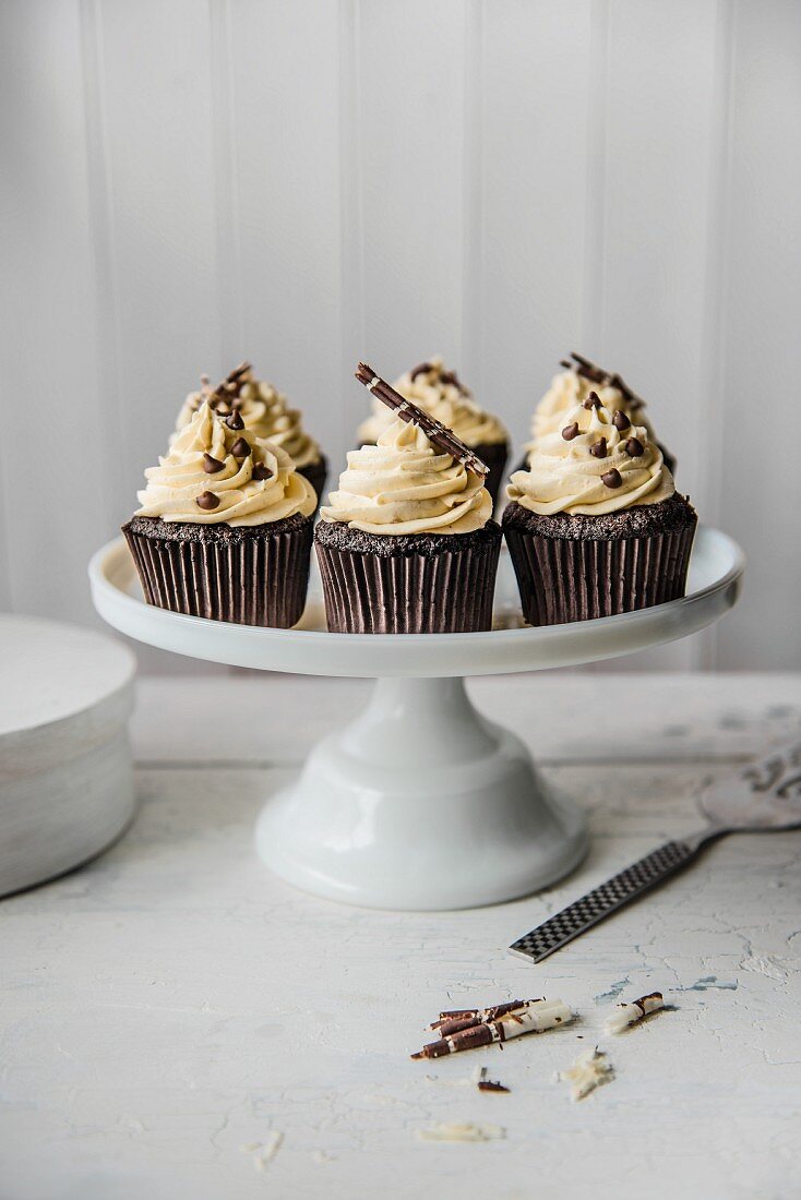 Schokoladencupcakes mit weisser Schokoladenglasur auf Kuchenständer