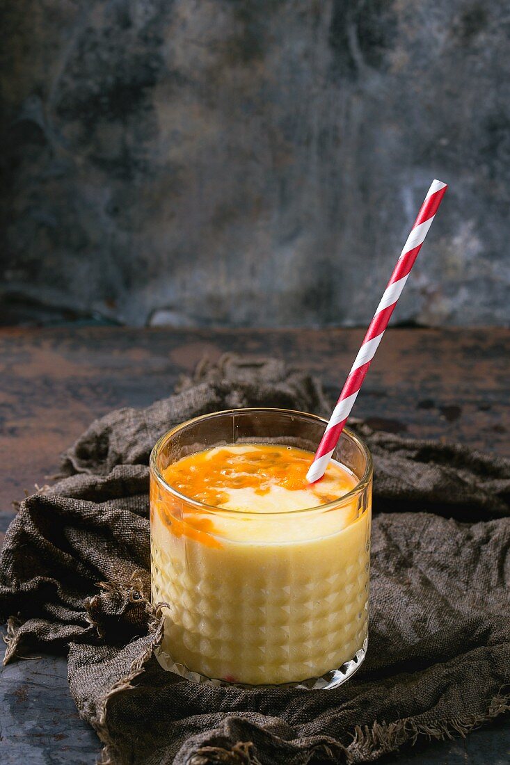Ein Glas Mango-Maracuja-Milchshake mit Strohhalm
