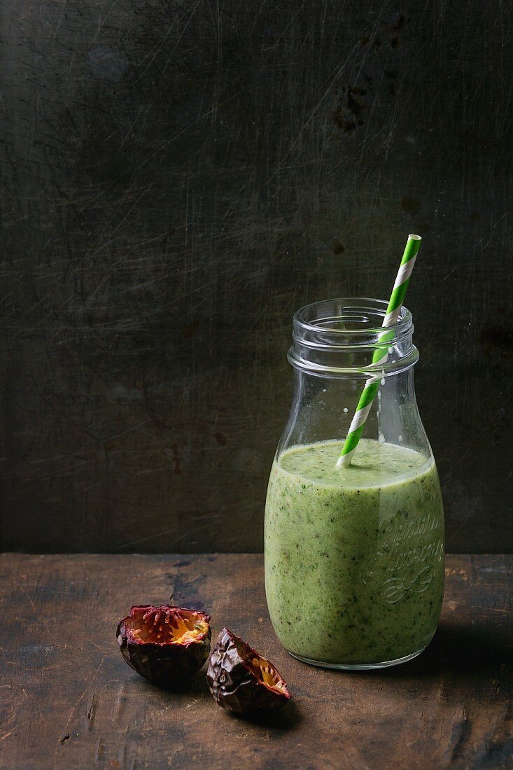 A bottle of kiwi & passionfruit milkshake with a straw on a wooden surface