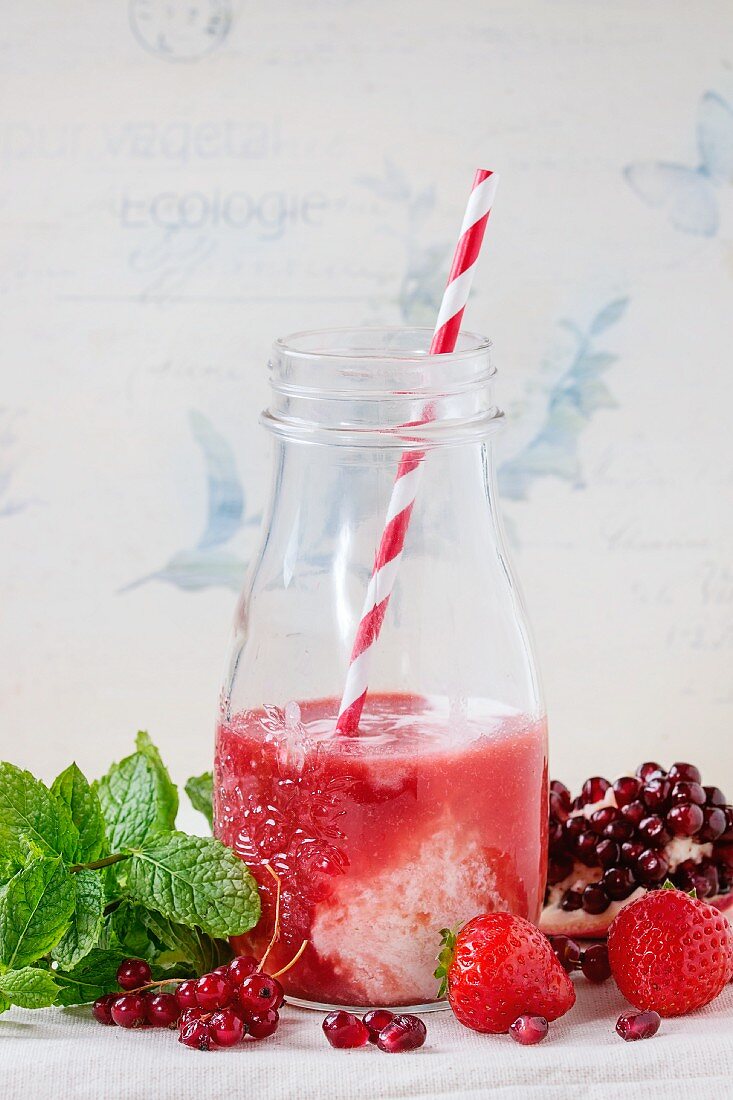 A bottle of strawberry & redcurrant milkshake with fresh berries and mint
