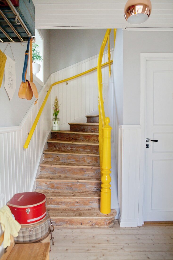 Rustikaler Holztreppenaufgang mit gelbem Handlauf und Treppenpfosten in renoviertem Altbau