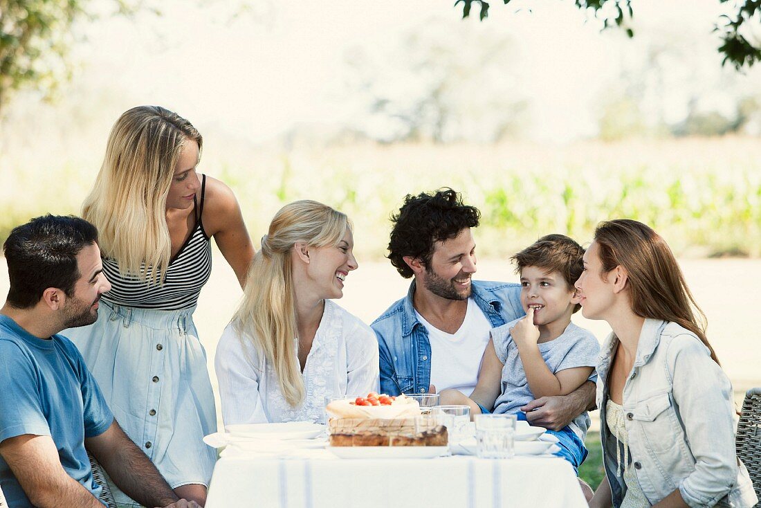 Familie und Freunde an einem Gartentisch