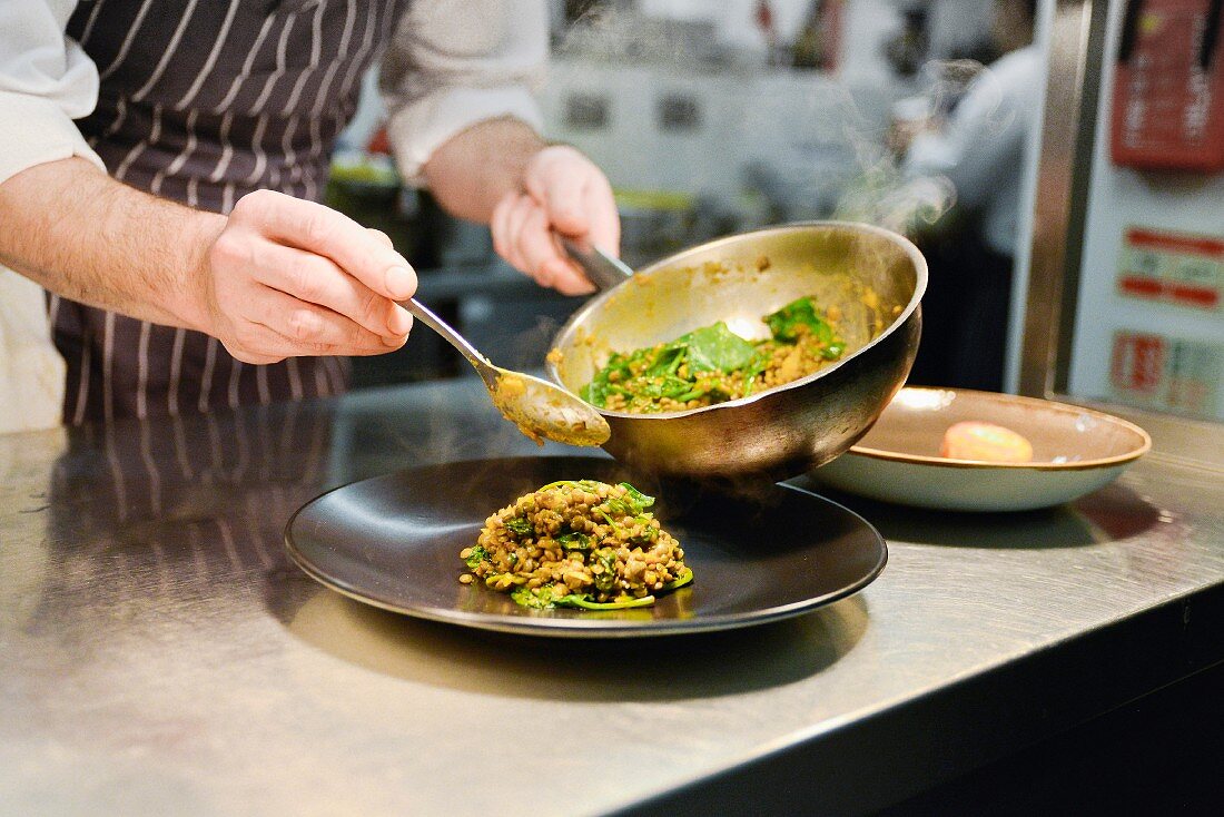 A chef plating up a lentil dish