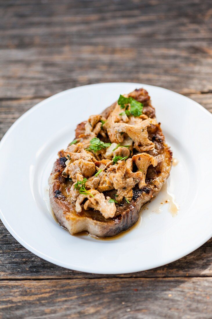 A grilled pork chop with chanterelle mushrooms and parsley