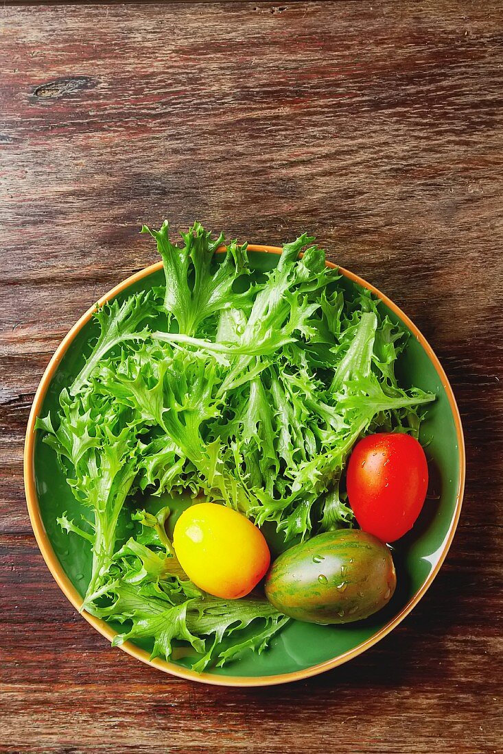 Frische grüne Salatblätter mit bunten Tomaten (Draufsicht)