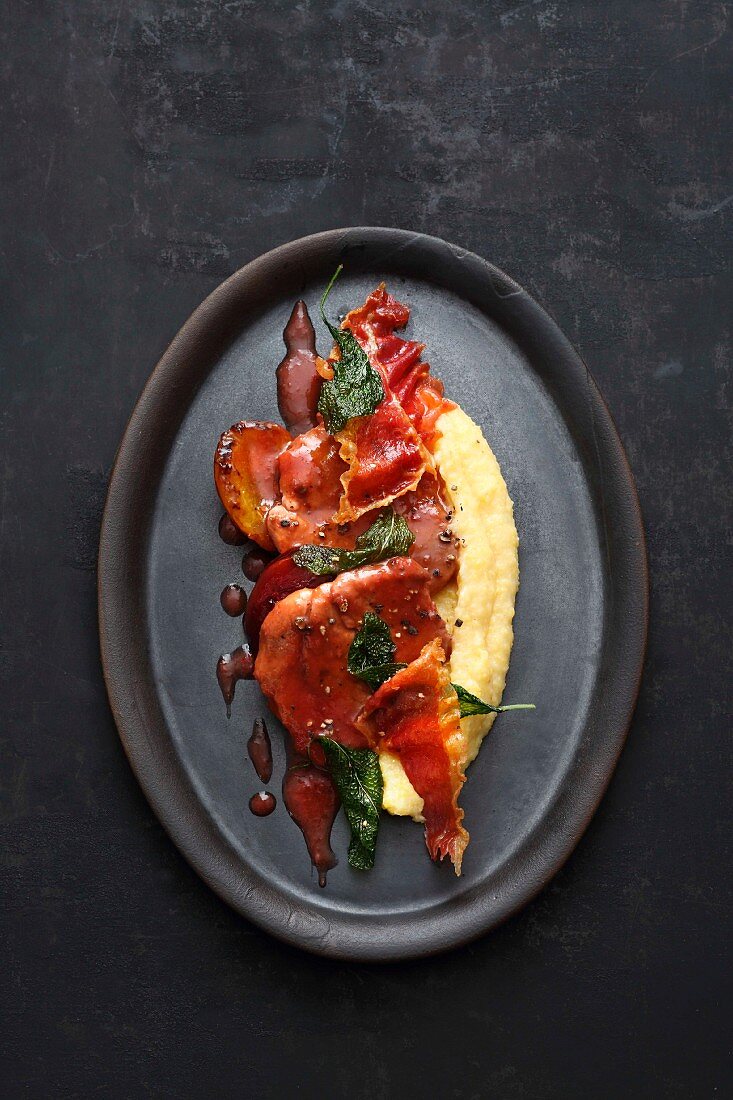 Pork escalope in sweet and sour plum sauce with ham crisps and polenta