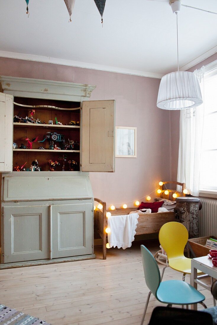 Kinderzimmer mit nostalgischem Holzbett und Lichterkette, Vintage Schrank und zeitgenössischem Spielzeug