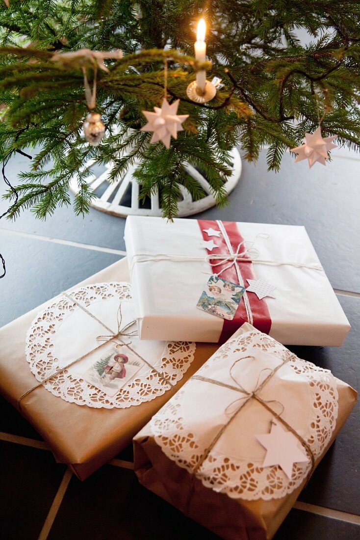 Gifts wrapped in vintage-style packaging below Christmas tree