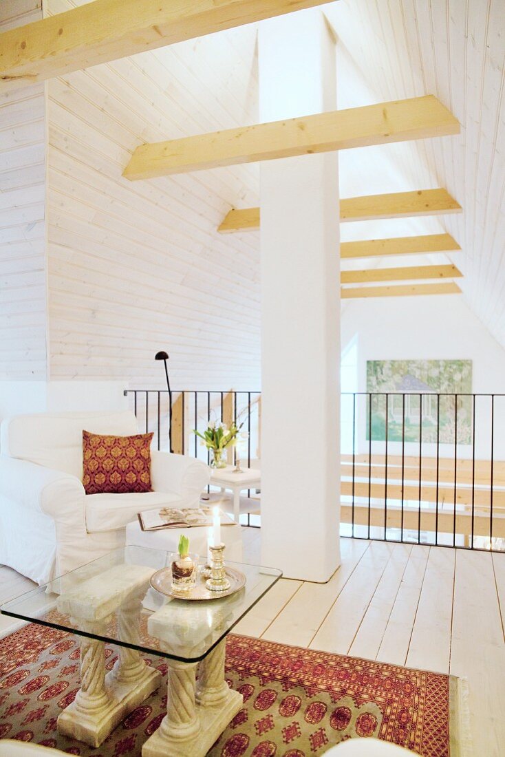 Loose-covered armchair and chimney in lounge on gallery under open gable ceiling