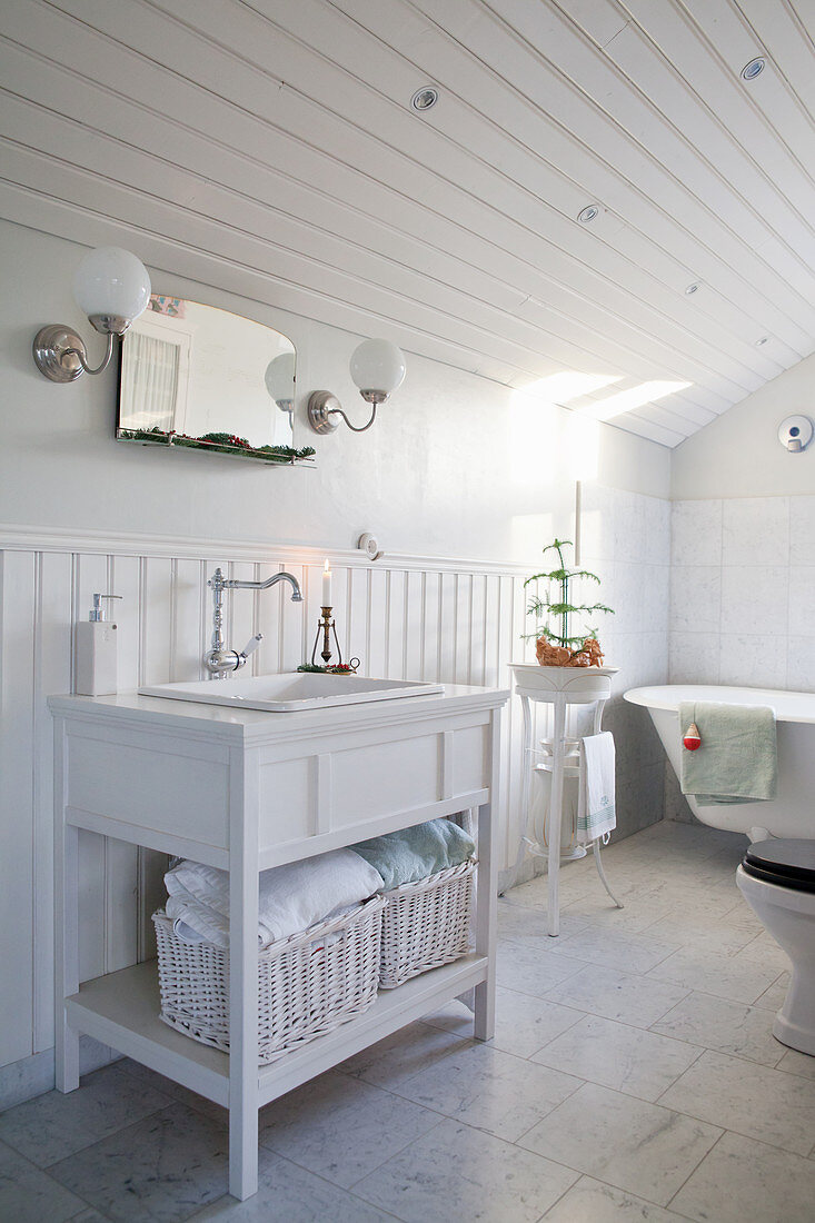 Washstand in white, wood-clad bathroom under sloping ceiling