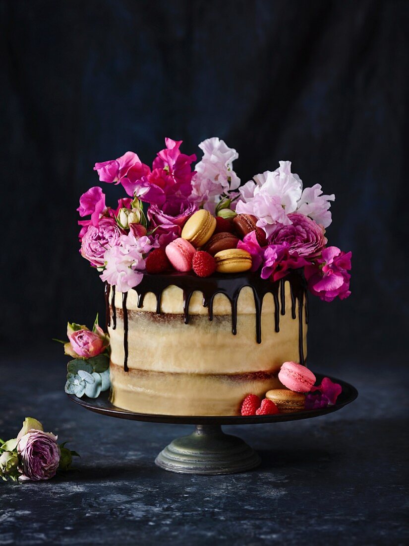 A naked cake with macarons and flowers
