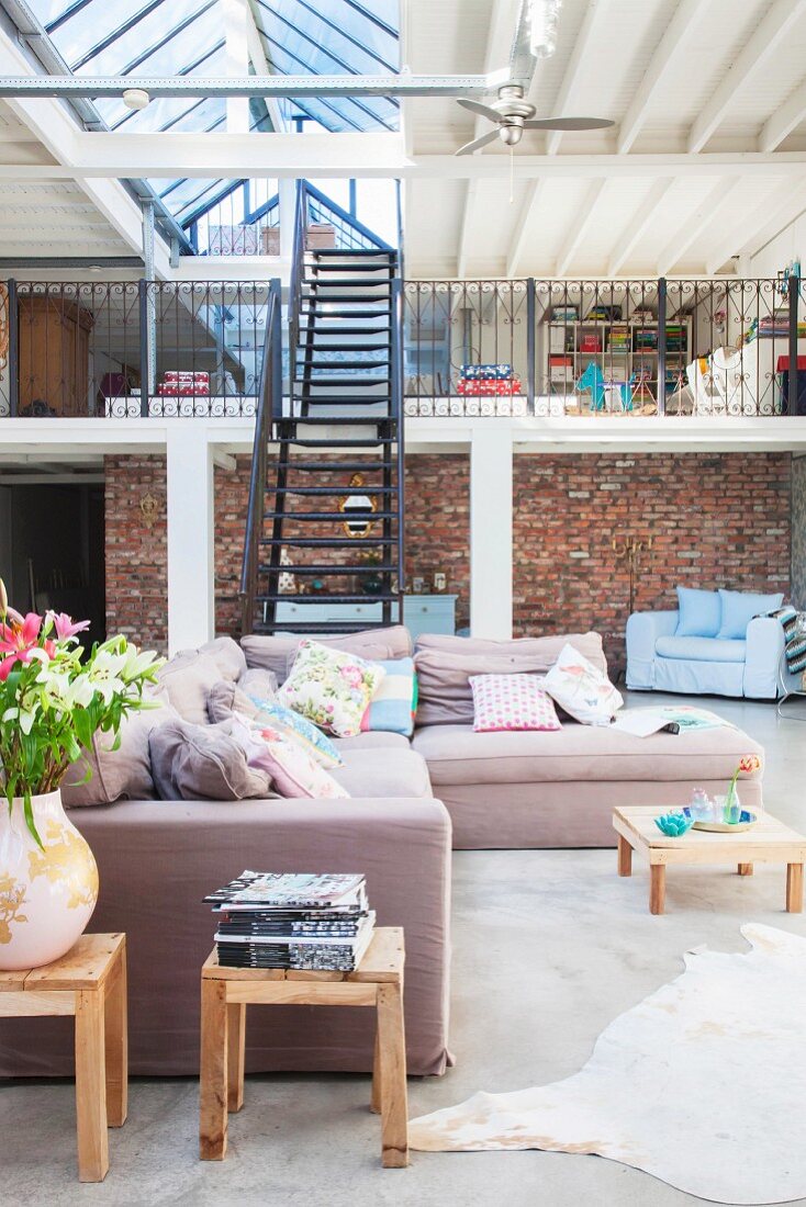 Comfortable pastel lounge area in front of black metal staircase leading to gallery