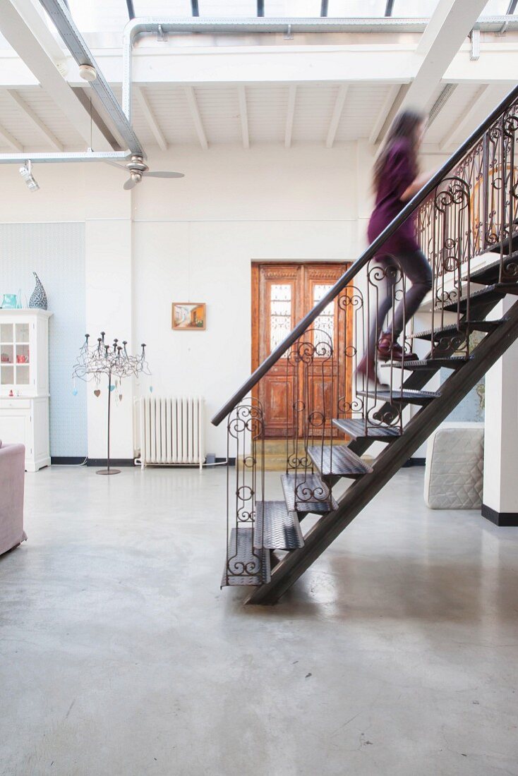 Stahltreppe mit kunsthandwerklichem Geländer in Loftwohnung mit Betonboden